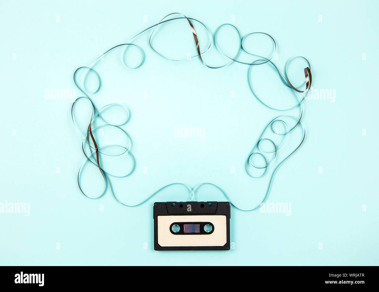 Analogue cassette tape on pastel blue background, 80s retro frame, lot of empty copy space. Stock Photo
