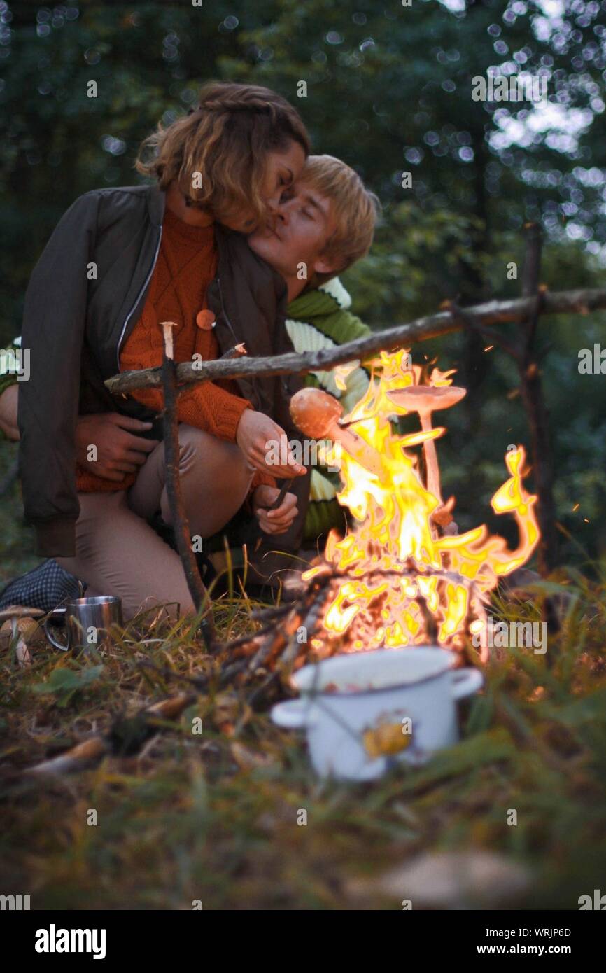 Romantic Couple Roasting Mushrooms In Forest Stock Photo