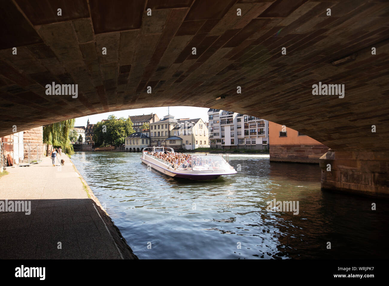 An open tour boat prepares to pass under the Pont St Martin on the Petite France canal in Strasbourg, France. Stock Photo