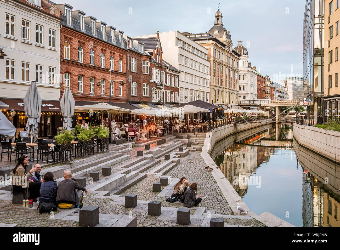 People sitting on a square at Aarhus canal in the center of the city, Denmark, July 15, 2019 Stock Photo