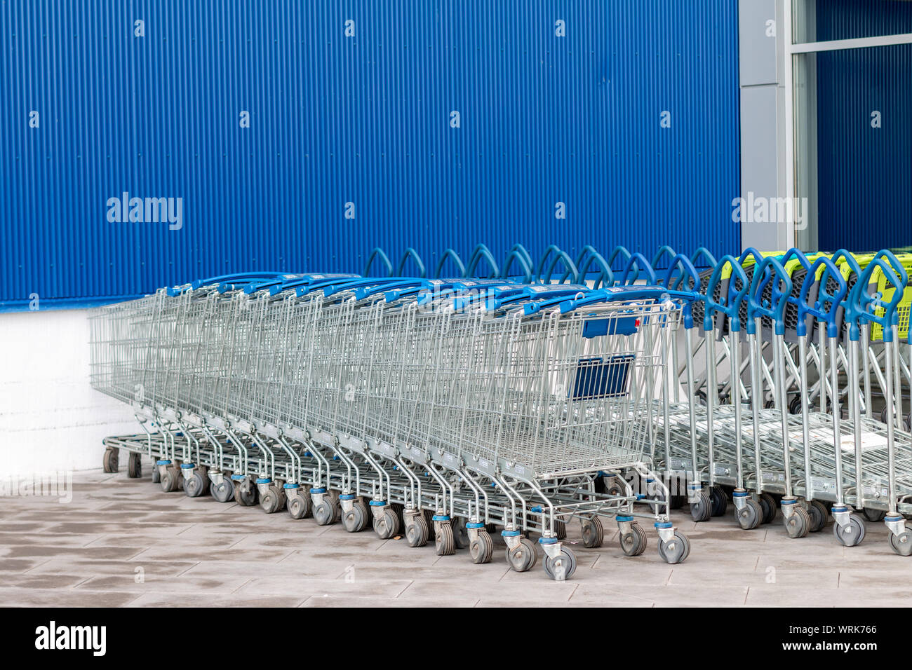 Shopping trolley parked near the shopping center. Brick wall, space for text Stock Photo