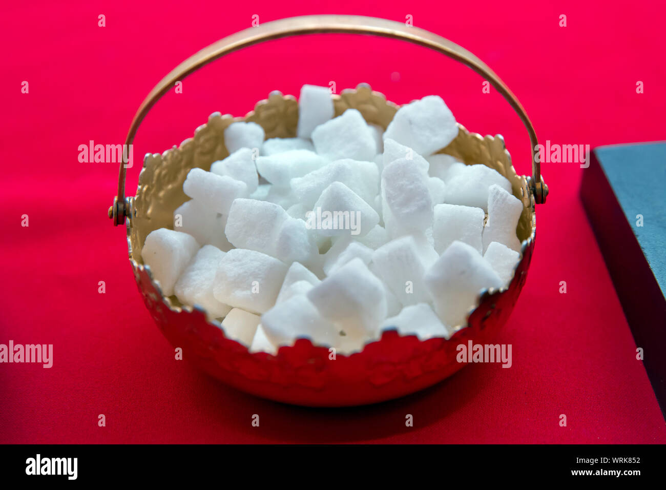 sugar bowl with a lump sugar isolated on a red background . Silver