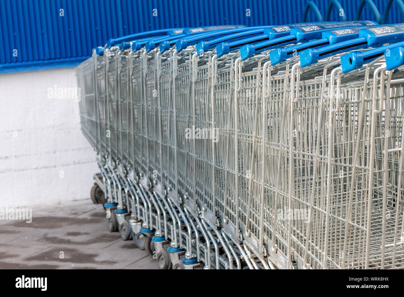 Shopping trolley parked near the shopping center. Brick wall, space for text Stock Photo