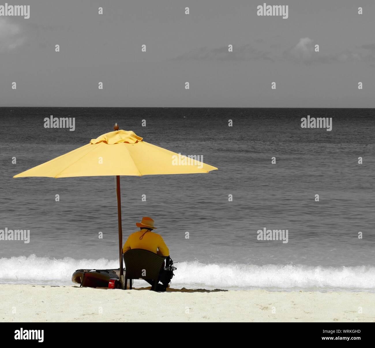 Rear View Of Man Sitting On Chair With Yellow Umbrella At Beach On Sunny Day Stock Photo Alamy