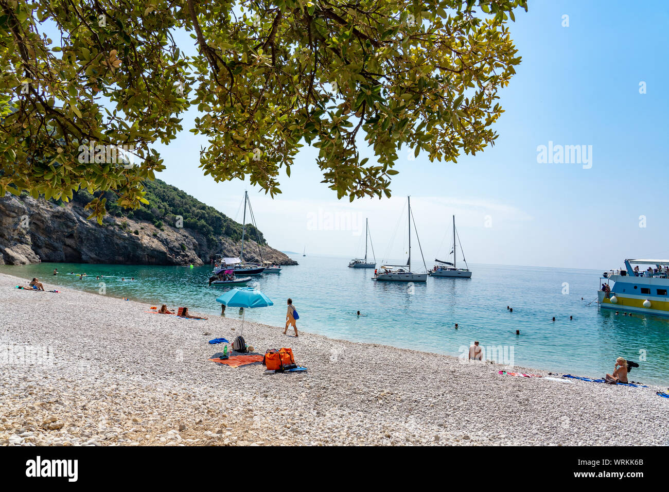 Lubenice beach with tousist and ships in Cres island Croatia with crystal clear turquoise water and atree shade Stock Photo