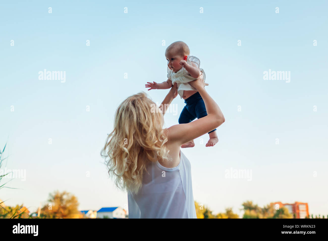 Young mother walking by summer river with baby girl. Woman lifting kid and  having fun with child. Family spends time together Stock Photo - Alamy