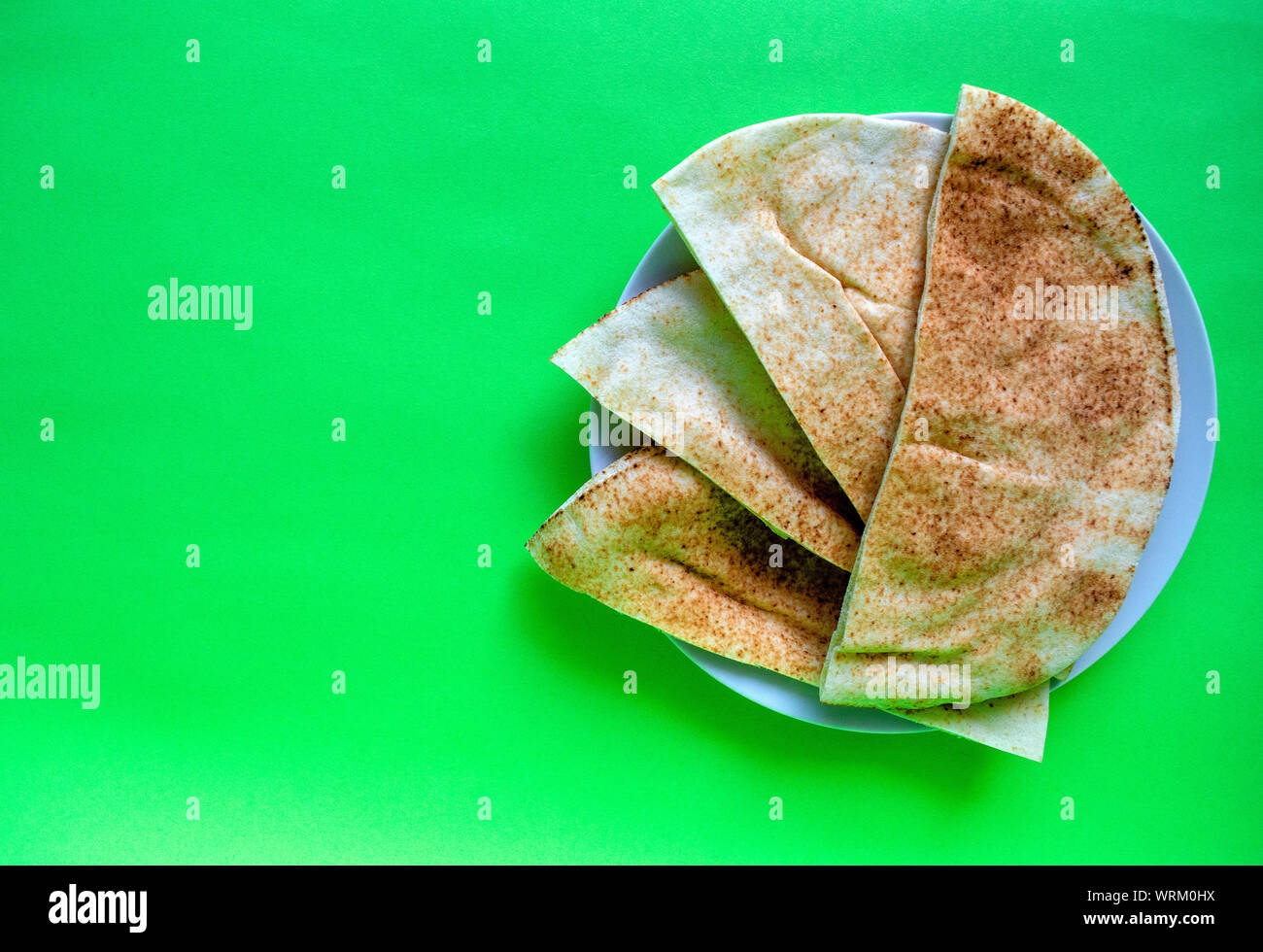 Famous traditional Arabic pita bread in white plate on green background
