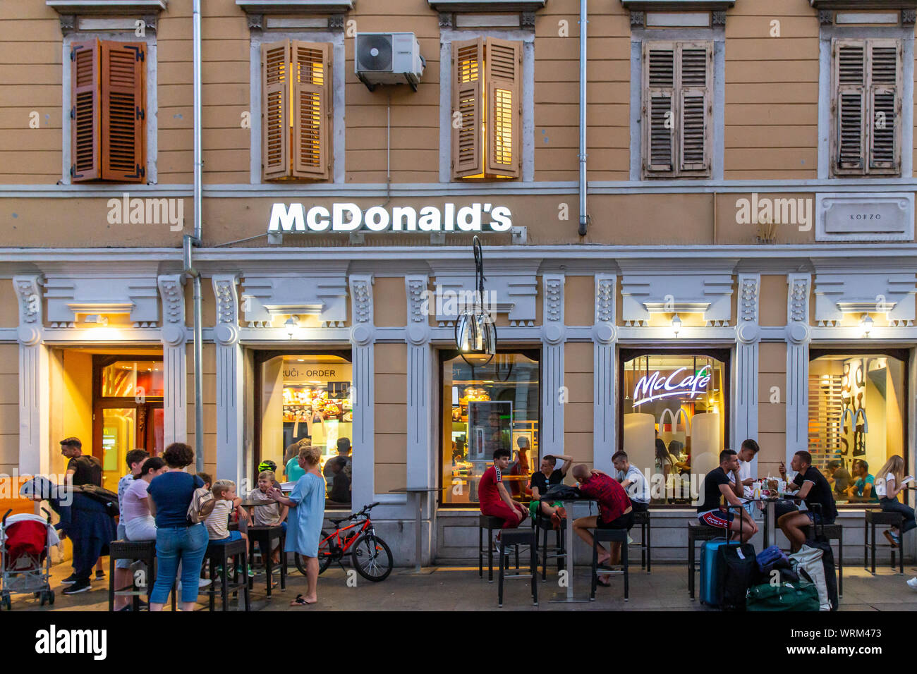 Rijeka's McDonalds on the Korzo main shopping street.  Customers eat their meals outside on a warm summer evening. Rijeka, Croatia, 2019 Stock Photo