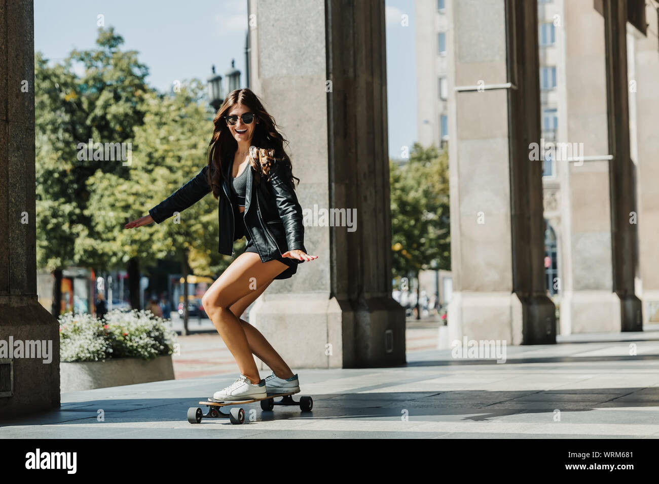 Beautiful young skater woman riding on her longboard in the city. Stylish  girl in street clothes rides on a longboard Stock Photo - Alamy