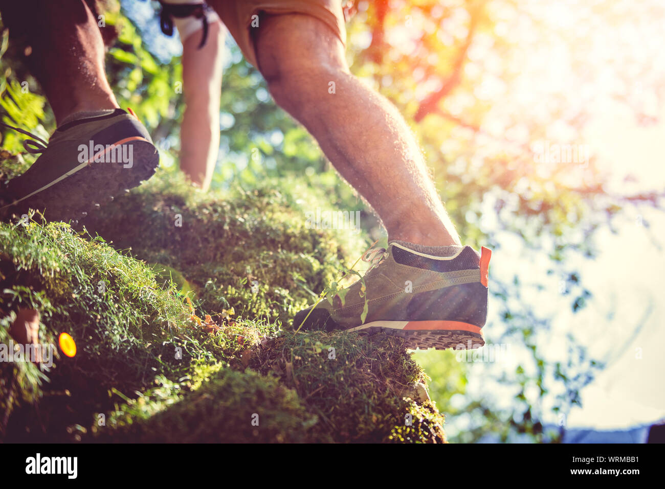Hikers climbing on a moss-covered boulders Stock Photo