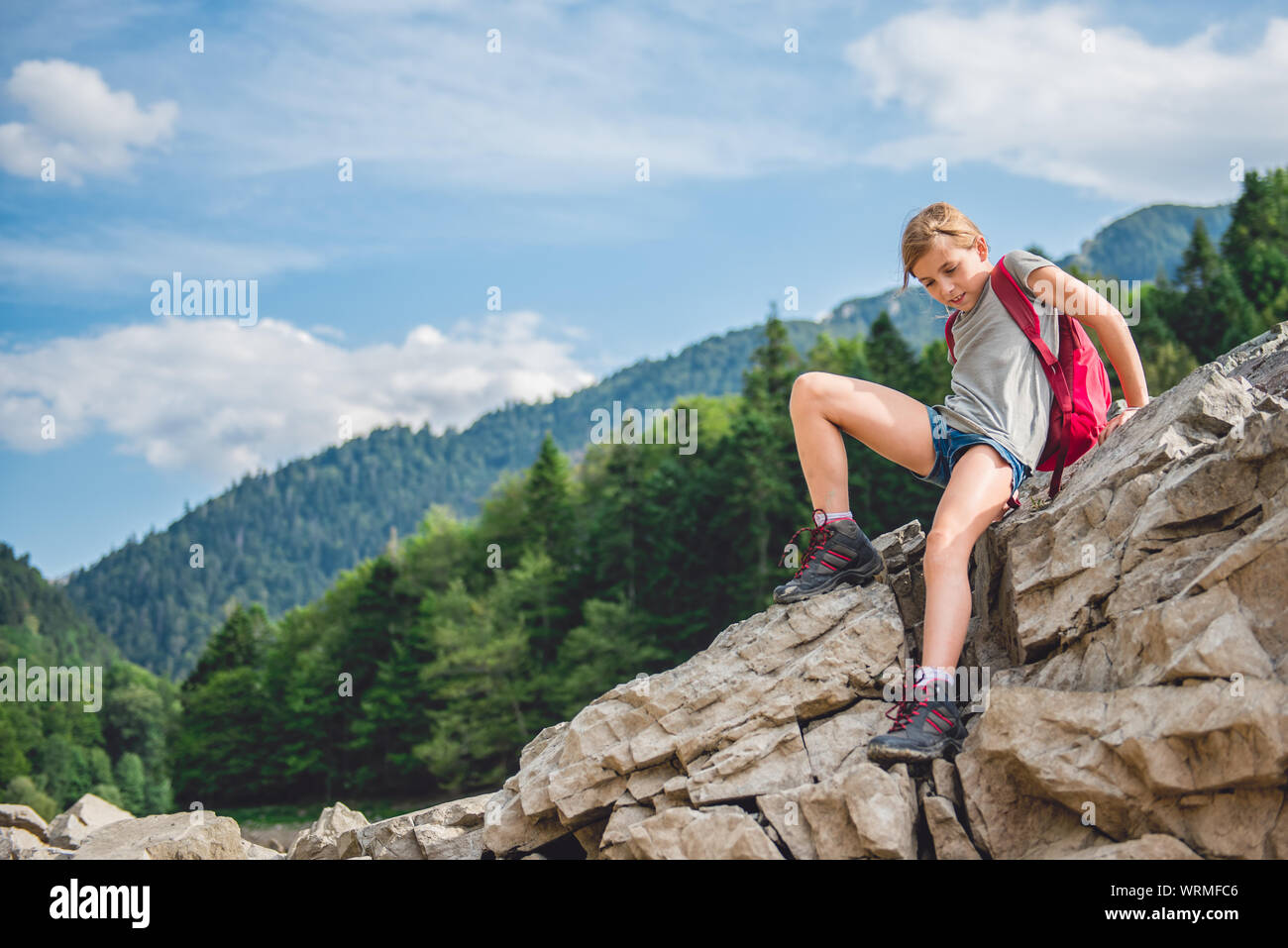 Hiker wearing grey shirt and backpack descends the mountain Stock Photo