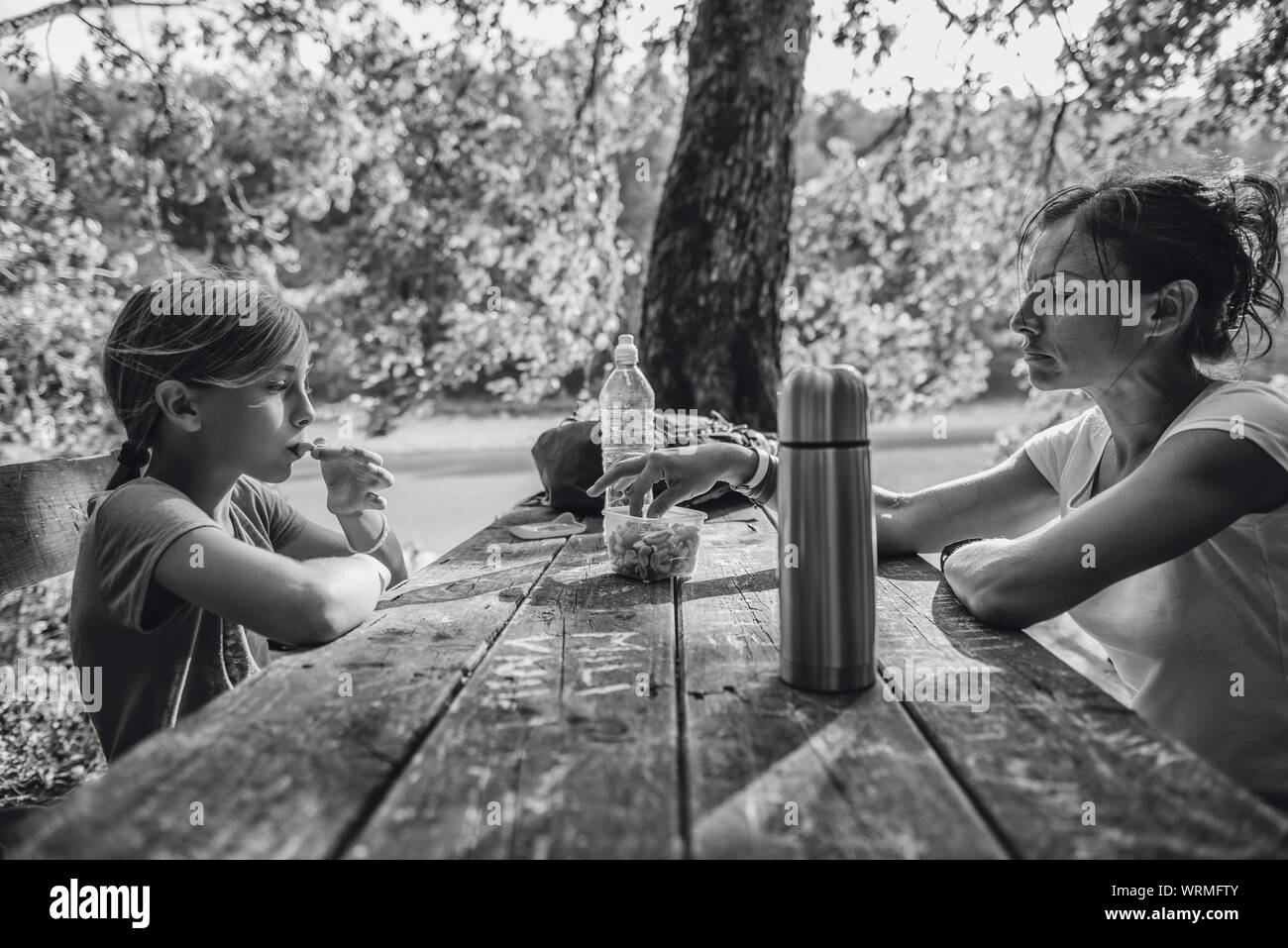 Mother and daughter eating healthy snack at a picnic table in the forest Stock Photo