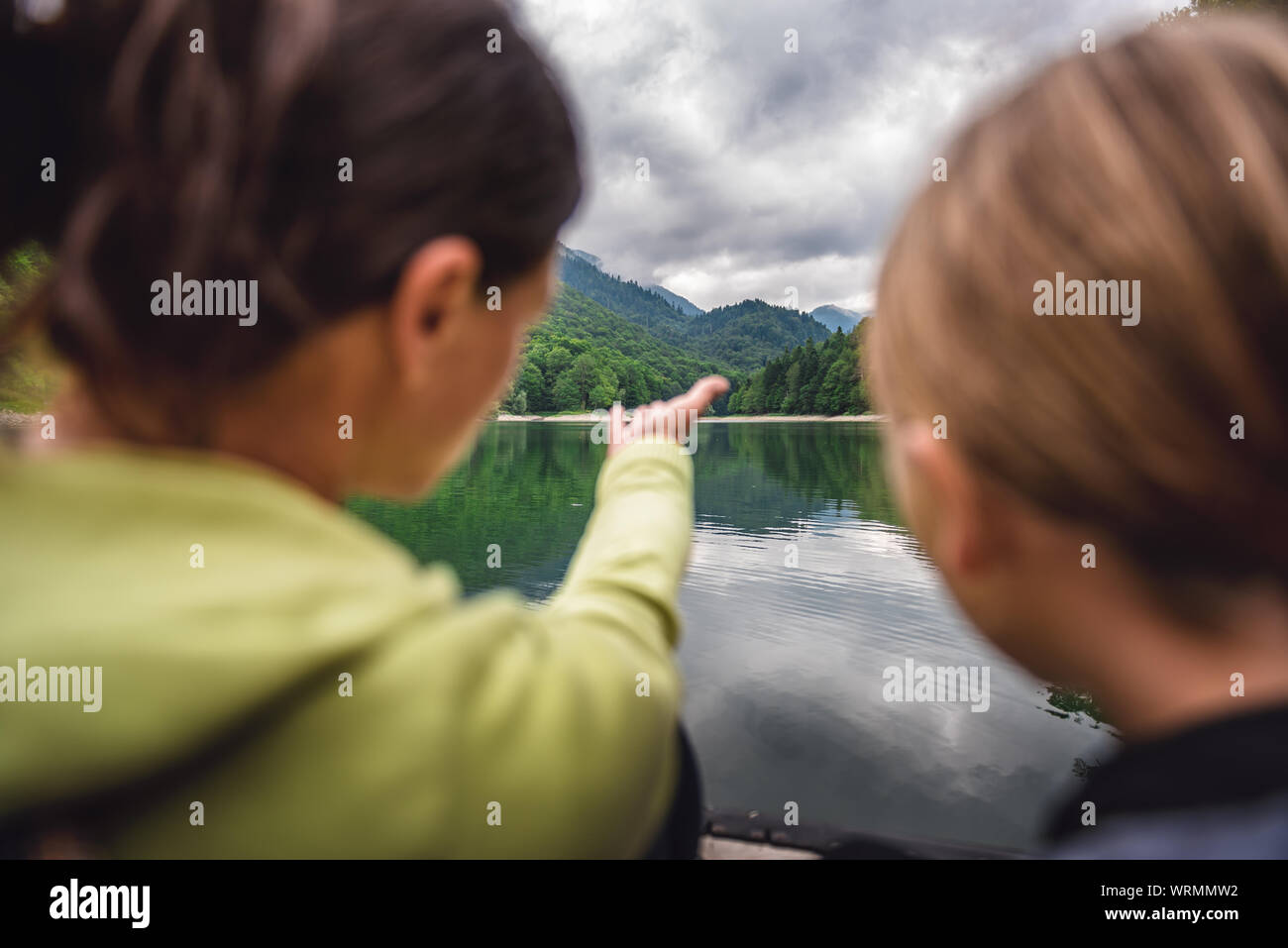 Mother and daughter enjoying by the mountain lake and foggy forest in morning Stock Photo