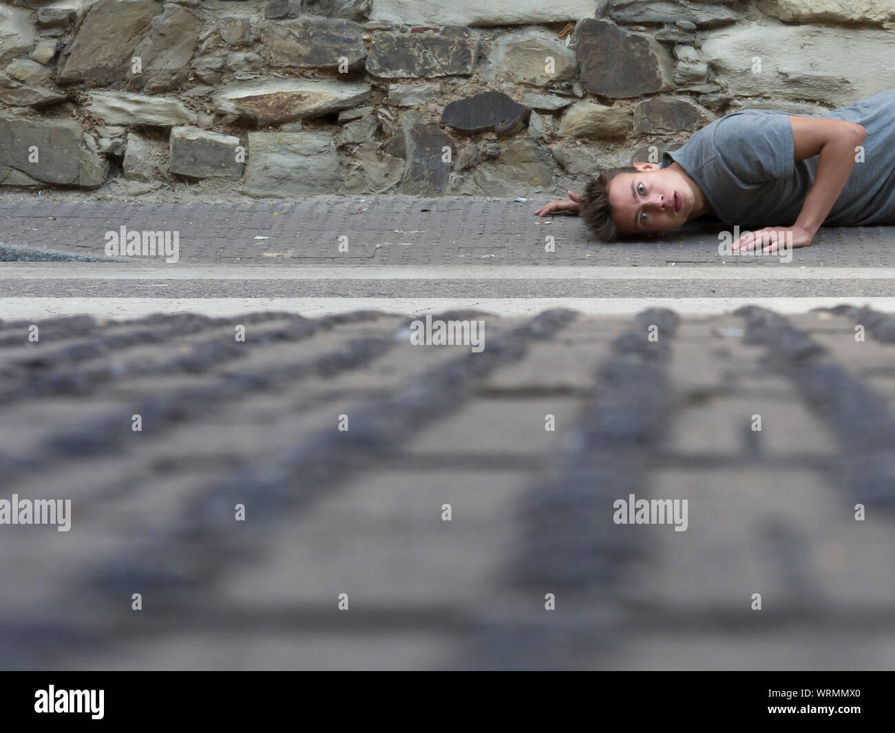 Surface Level Of Young Man Lying On Sidewalk Stock Photo