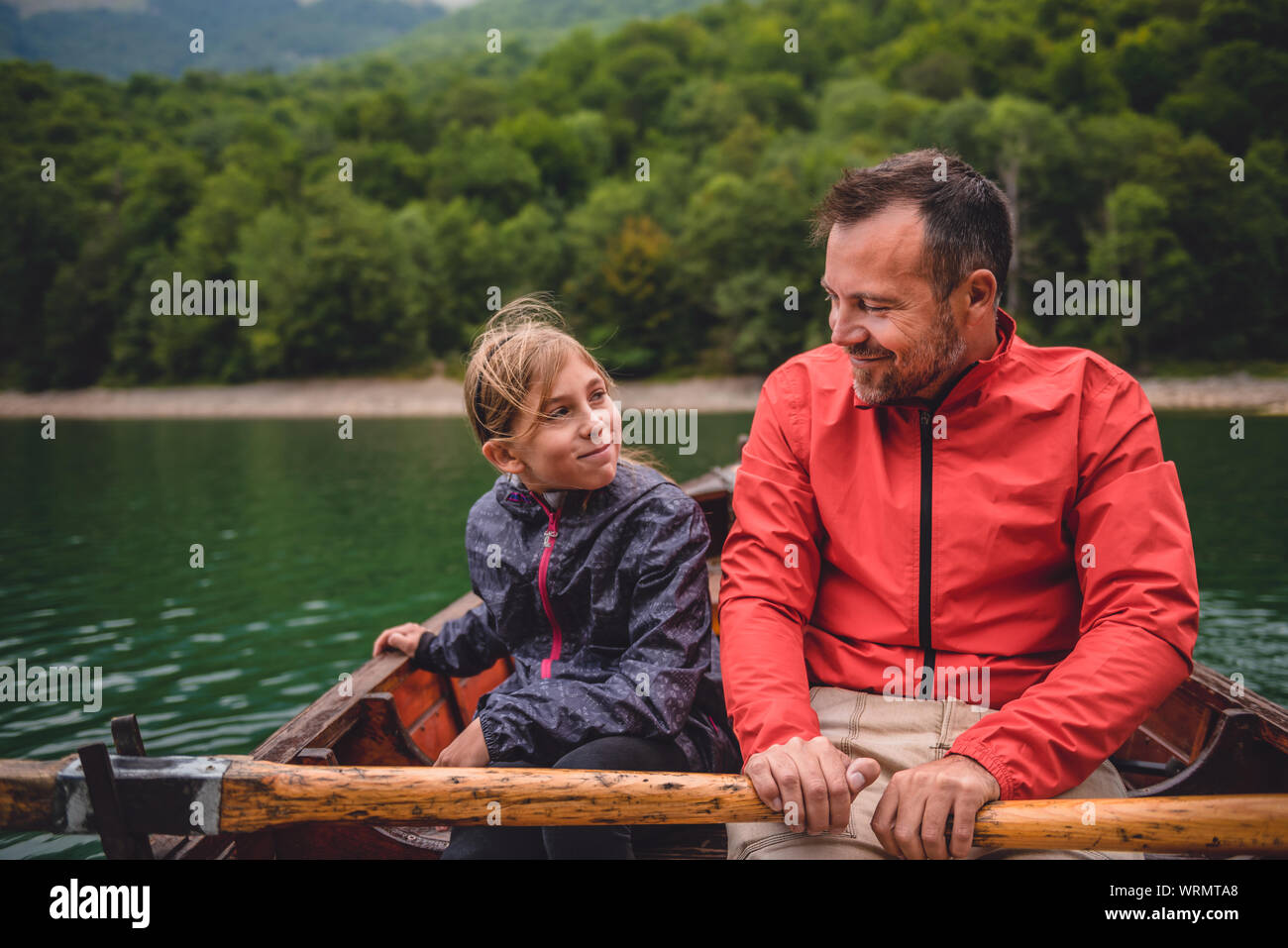 Father and daughter rowing a boat on a mountain lake Stock Photo