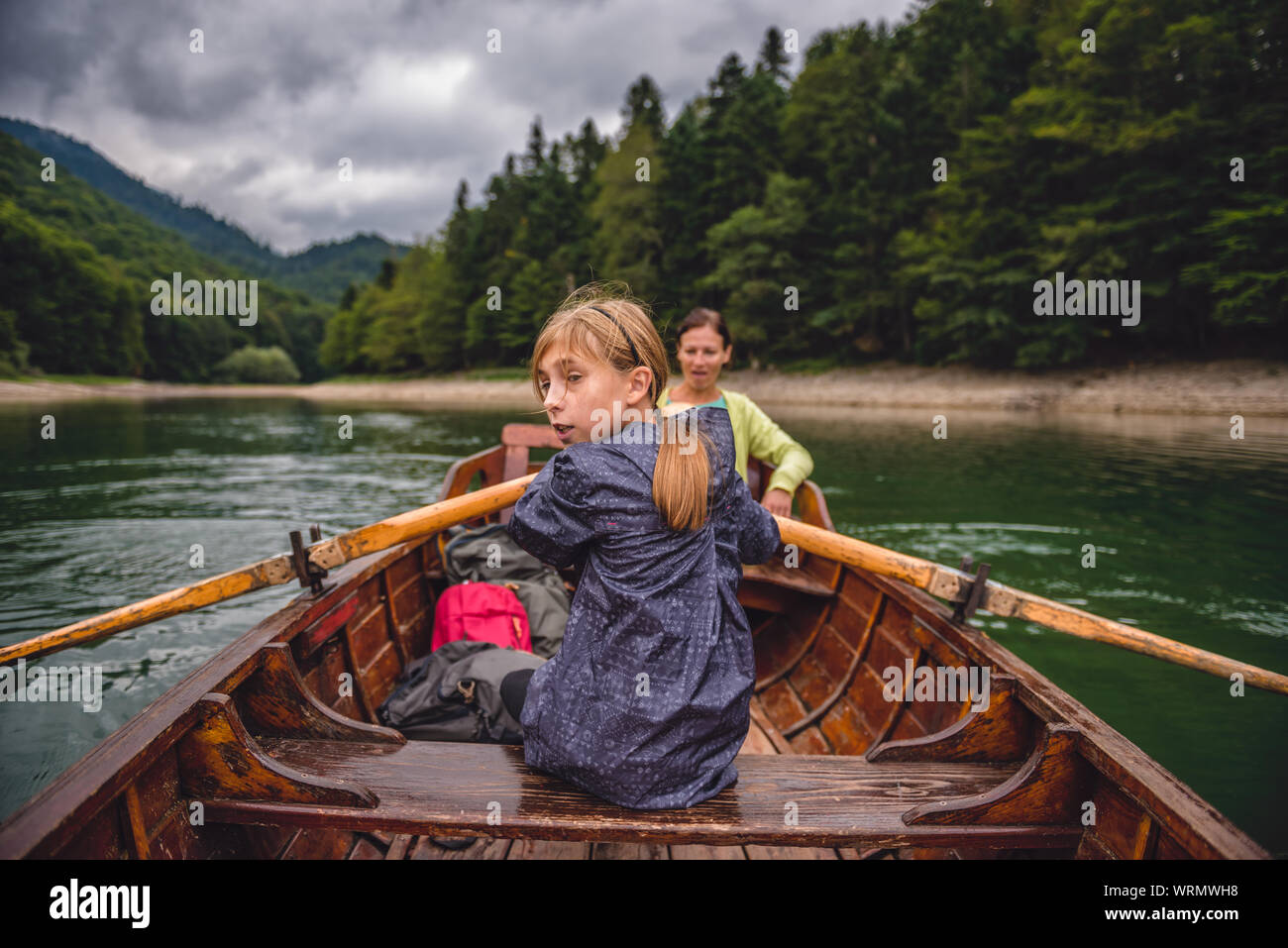 Mother and daughter rowing a boat on a mountain lake Stock Photo