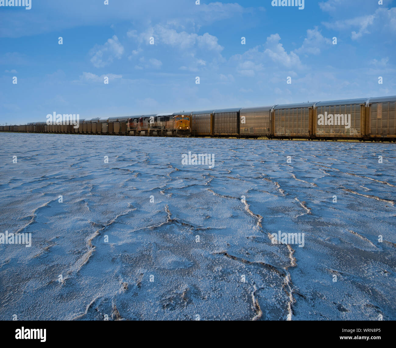Digital composite of a freight train running over cracked salt flats