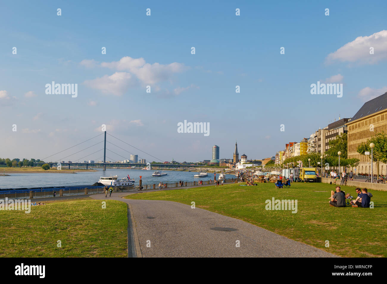 Rhine Riverside Crowd of people sit, hang out and enjoy beautiful day on park at ...