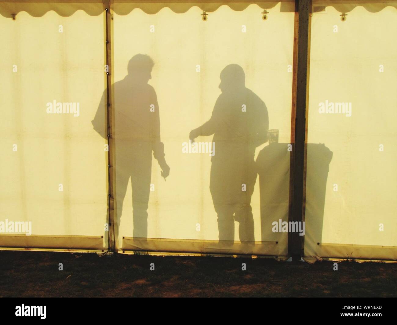 Shadows Of Men Communicating In Tent Stock Photo