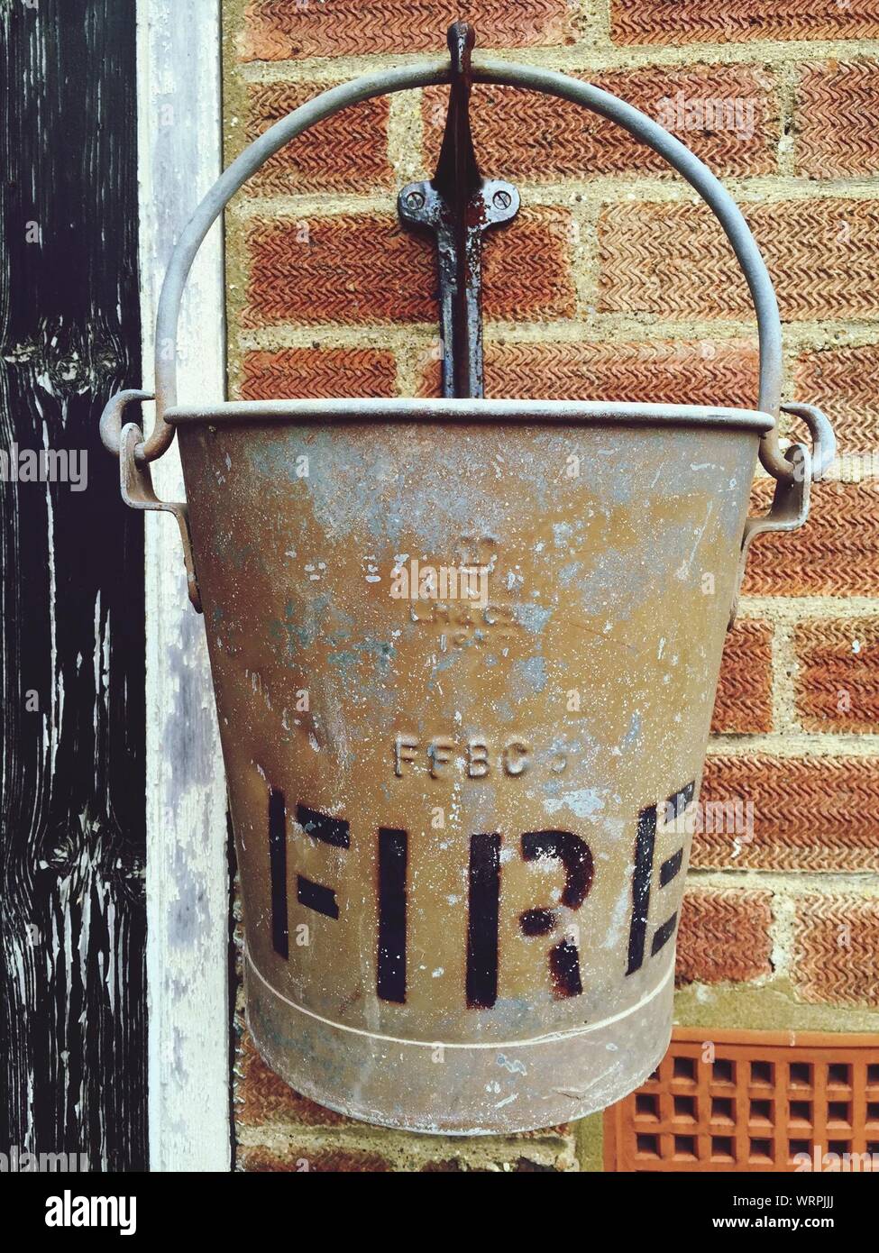 Close-up Of Bucket Hanging With Text Against Wall Stock Photo