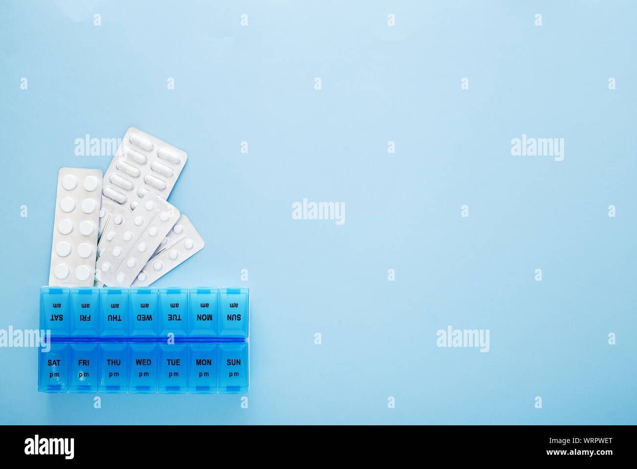 blue plastic 14 day pill box with pills on blue background. Top view. Stock Photo