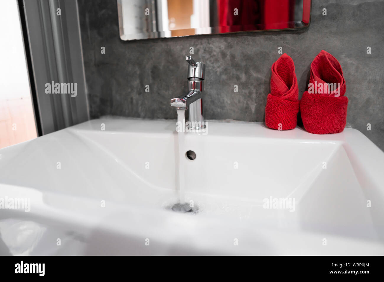 Running Water From Modern Stainless Steel Faucet In White Sink