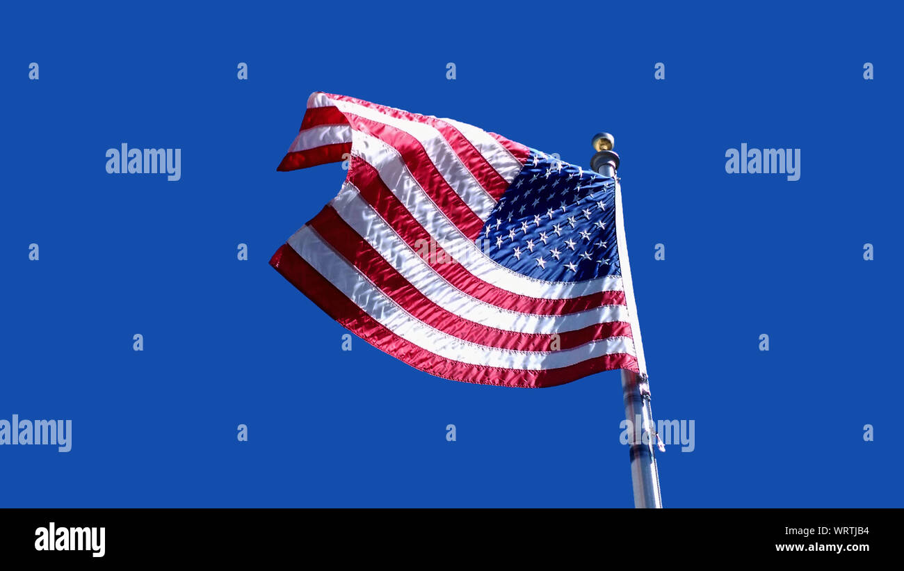 American Flag Waving Against A Clear Blue Sky Stock Photo