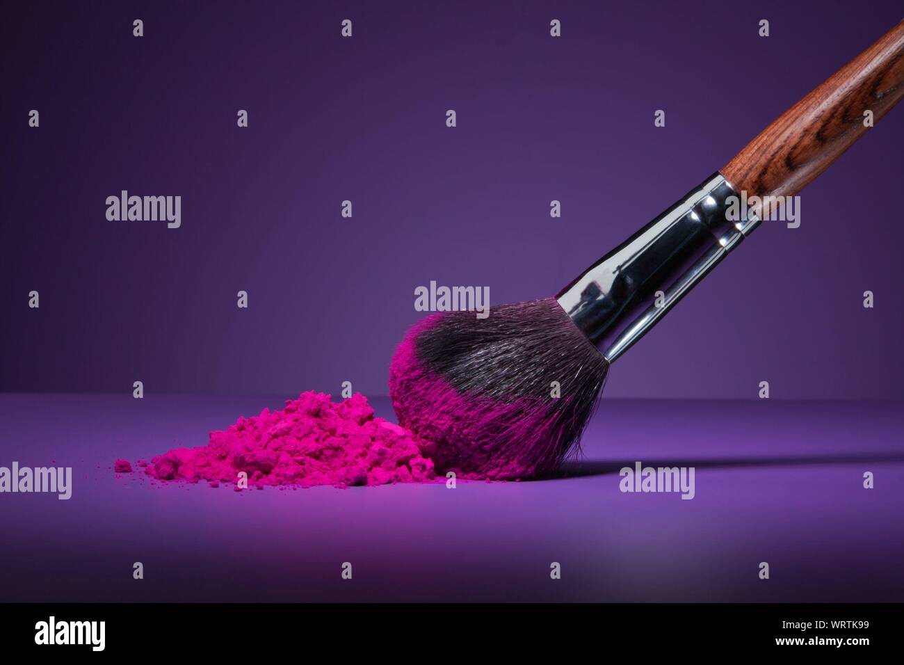Close-up Of Make-up Brush And Pink Face Powder On Purple Table Stock Photo