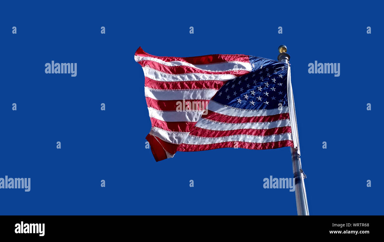 American Flag Waving Against A Clear Blue Sky Stock Photo