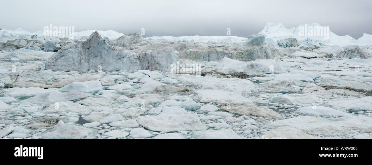 Global Warming and Climate Change - Icebergs and ice from melting glacier in icefjord in Ilulissat, Greenland. Aerial photo of arctic nature ice landscape. Unesco World Heritage Site. Panoramic banner Stock Photo