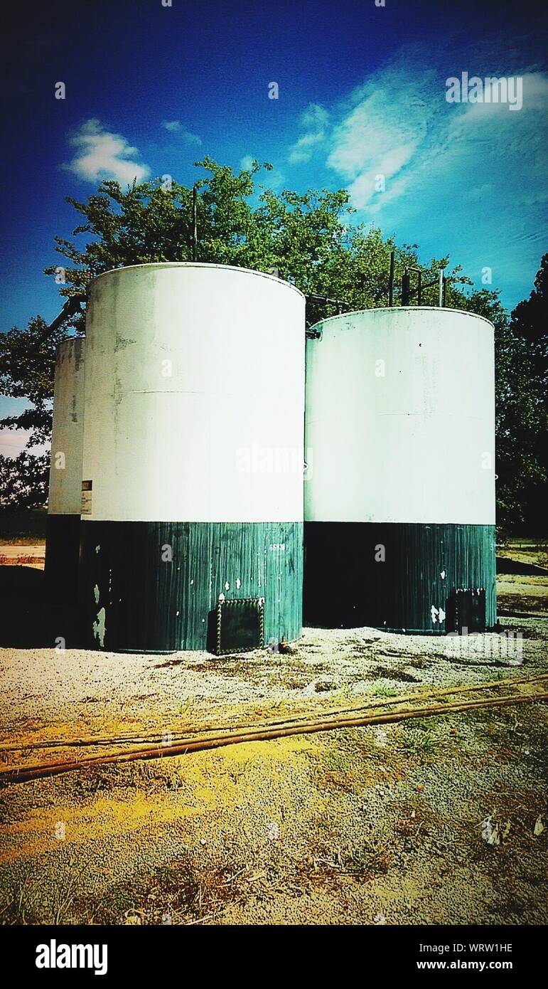 Oil Storage Tanks On Field Against Sky Stock Photo