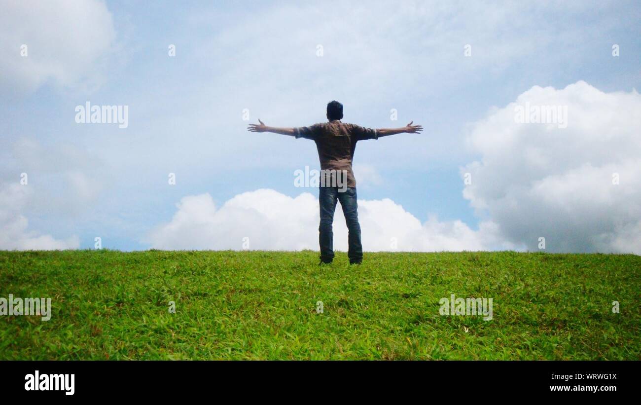 Rear View Of Man Standing On Hill With Arms Outstretched Stock Photo ...