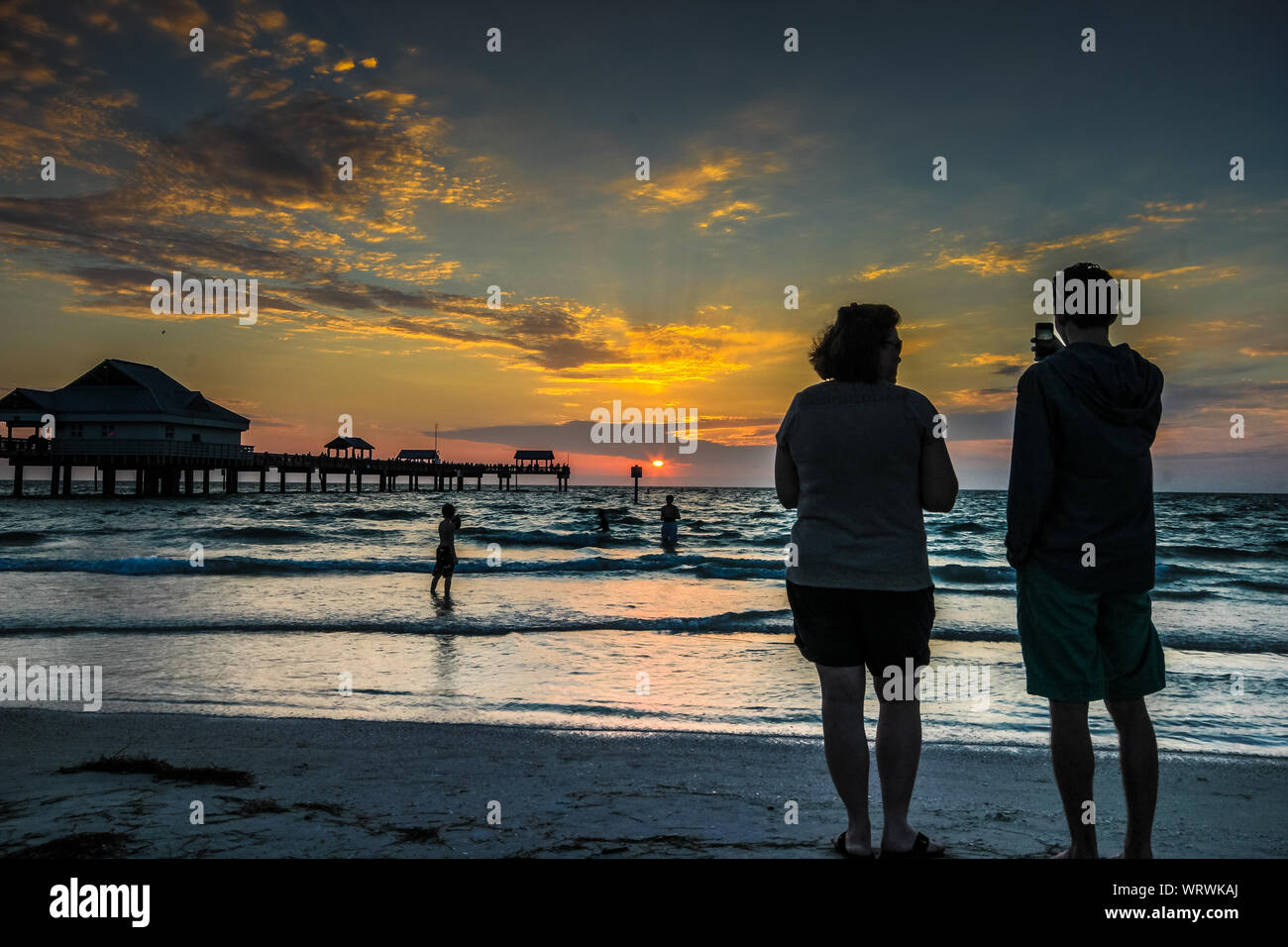 American looking male and female watching sunset on the beach - Senior lifestyle Stock Photo