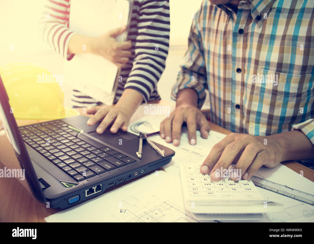 Two colleagues discussing data working with construction plan in office. Stock Photo