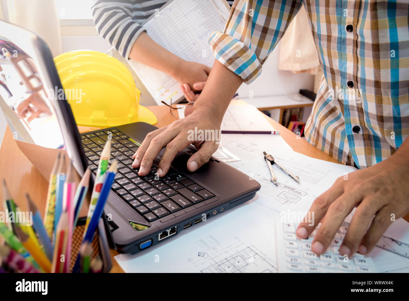 Two colleagues discussing data working with construction plan in office. Stock Photo