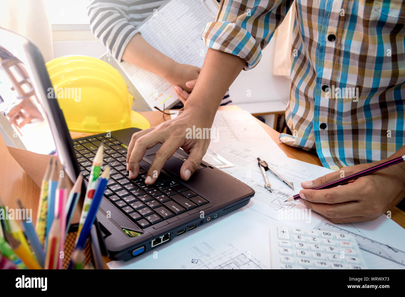 Architect with partner working with laptop on construction plan in office Stock Photo