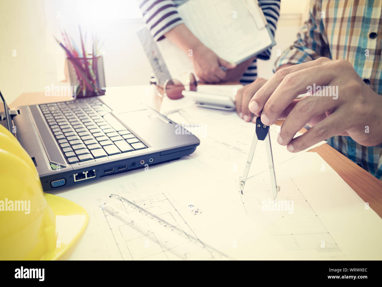 Architect with partner working with dividers on construction plan in