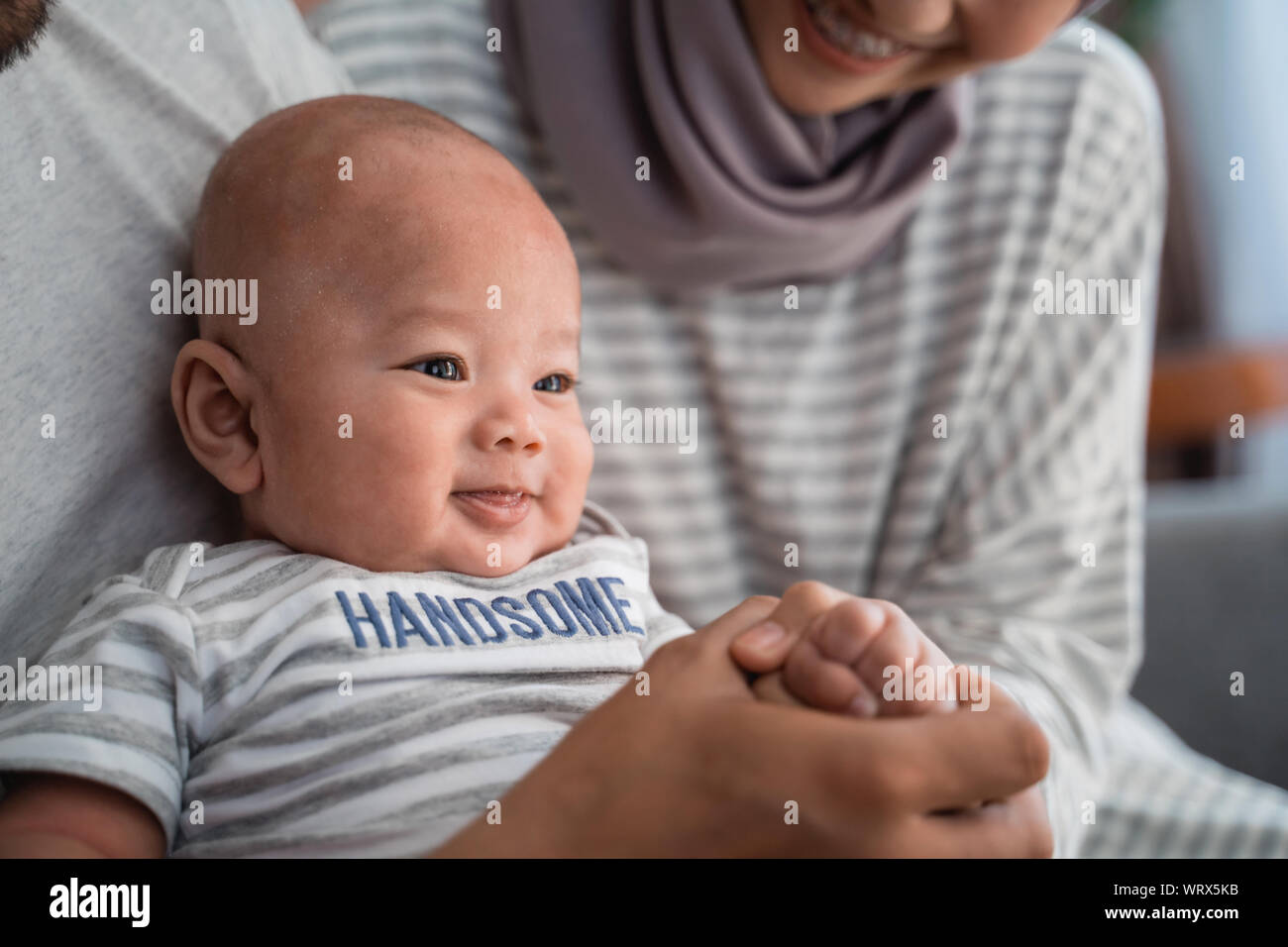 baby boy smiling while sitting on parent's lap Stock Photo