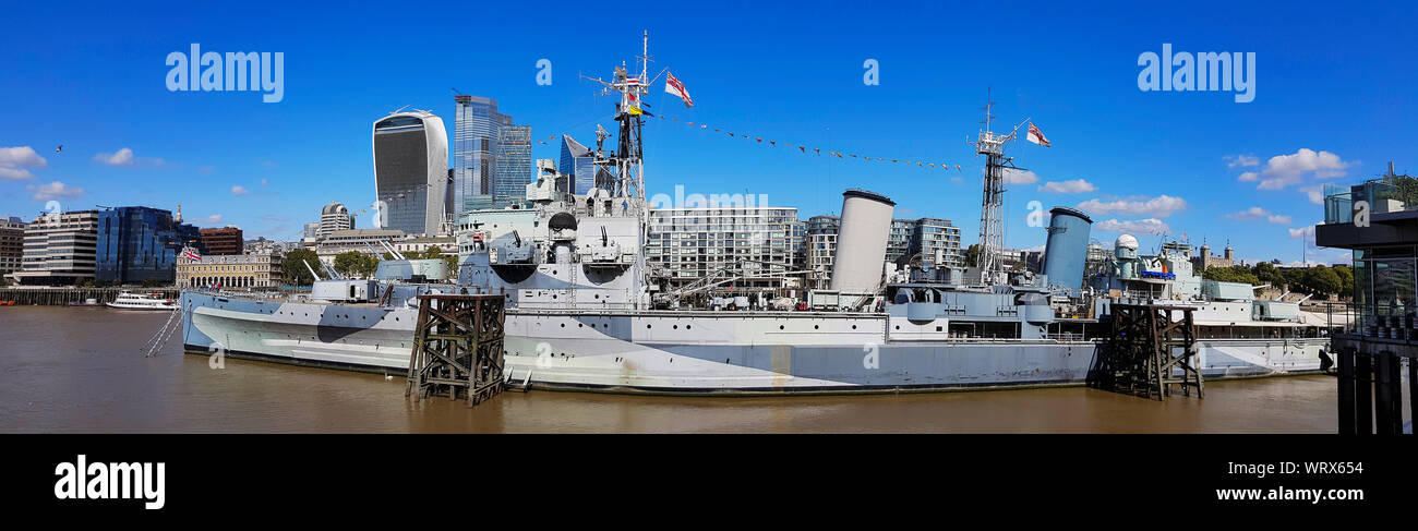 Panoramic view of HMS Belfast, surviving Second World War Royal Navy warship, now warship Museum operated by the Imperial War Museum, over blue sky. Stock Photo