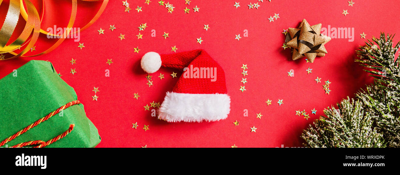 Christmas gift, Santa hat, gift, tree branches on red background with ...