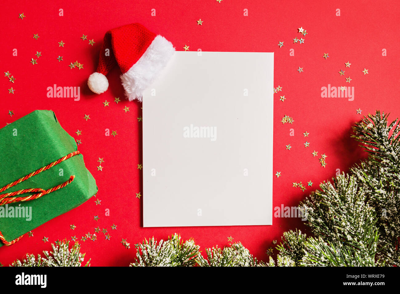 Blank of paper with Santa hat, gift, tree branches on red background ...