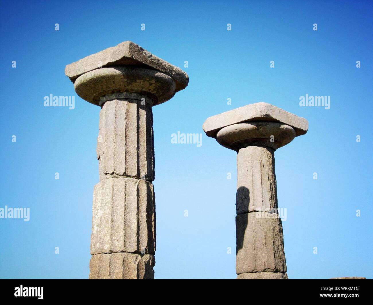 High Section Of Historic Temple Columns Against Clear Blue Sky Stock Photo