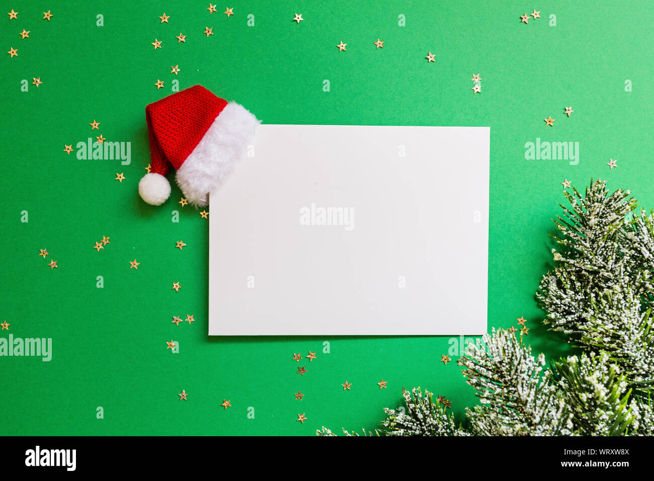 Blank of paper with red Santa hat, christmas tree branches on green ...