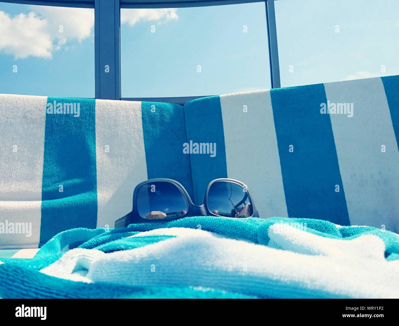 Sunglass And Towel On Deck Chairs Against Glass Window Stock Photo Alamy