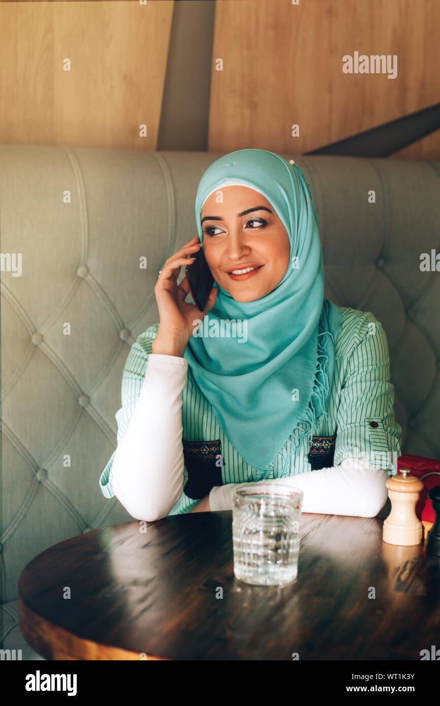 Beautiful young arabic girl in hijab talking by phone at cafe Stock ...