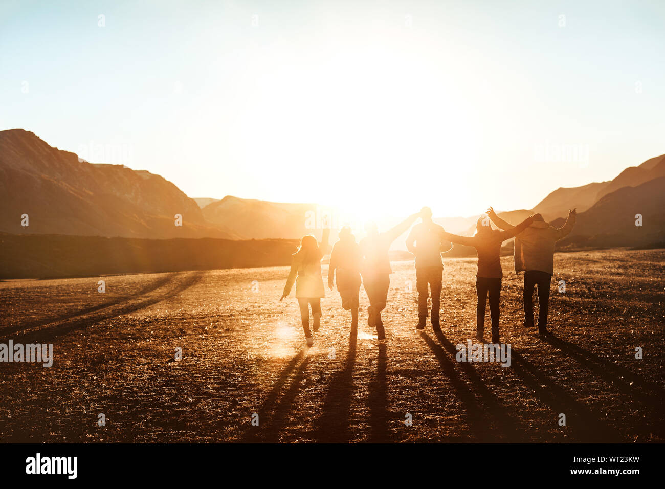 Big group of happy friends or tourists runs to sunset and having fun Stock Photo