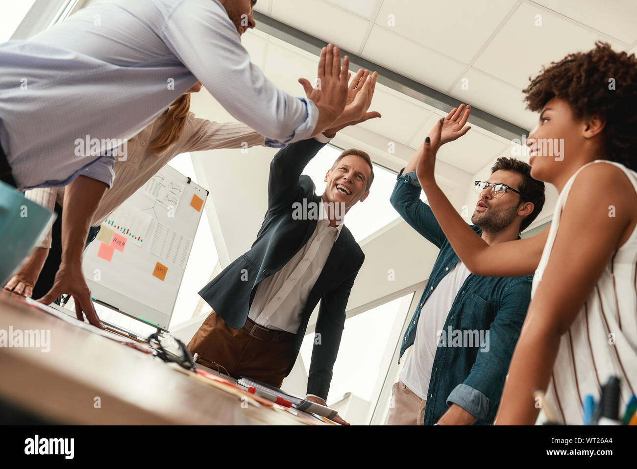 Success Business people giving each other high-five and smiling while working together in the modern office. Teamwork Stock Photo
