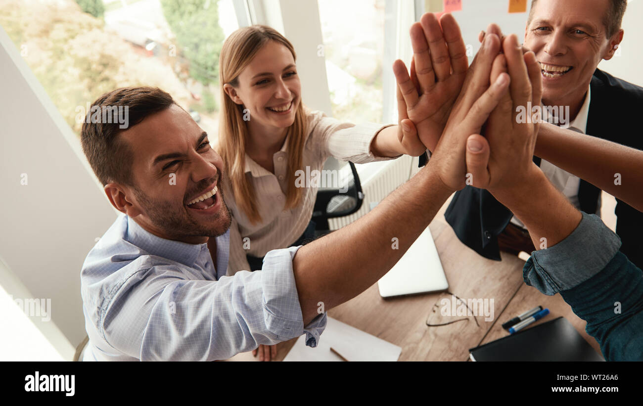 Successful team Business people giving each other high-five and smiling while working together in the modern office. Teamwork. Success Stock Photo