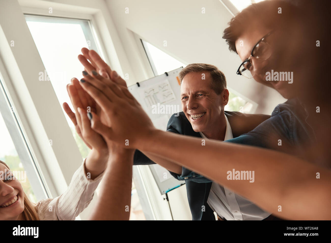 We are the best team Business people giving each other high-five and smiling while working together in the modern office. Teamwork. Success Stock Photo