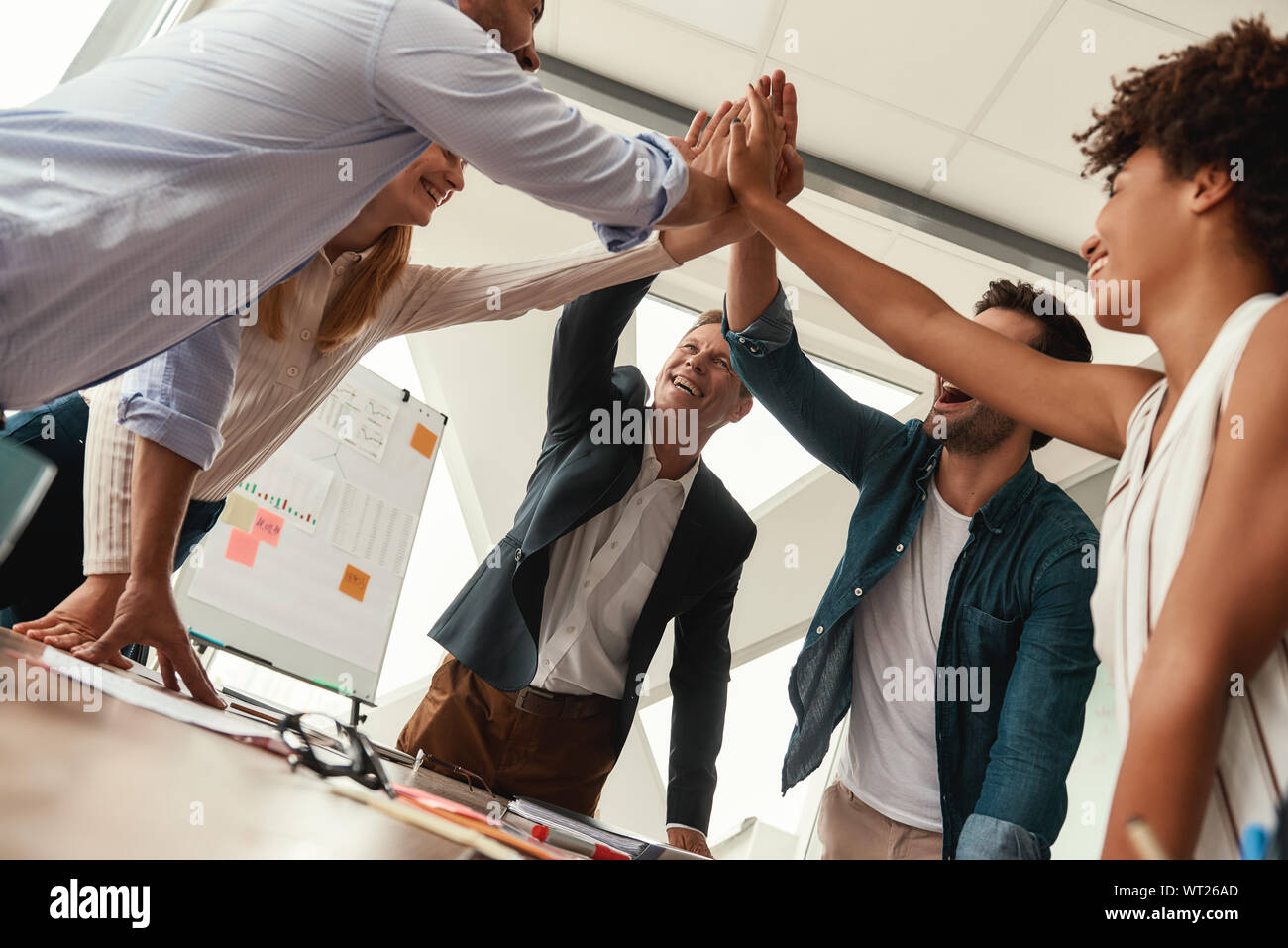 We did it Business people giving each other high-five and smiling while working together in the modern office. Teamwork. Success Stock Photo